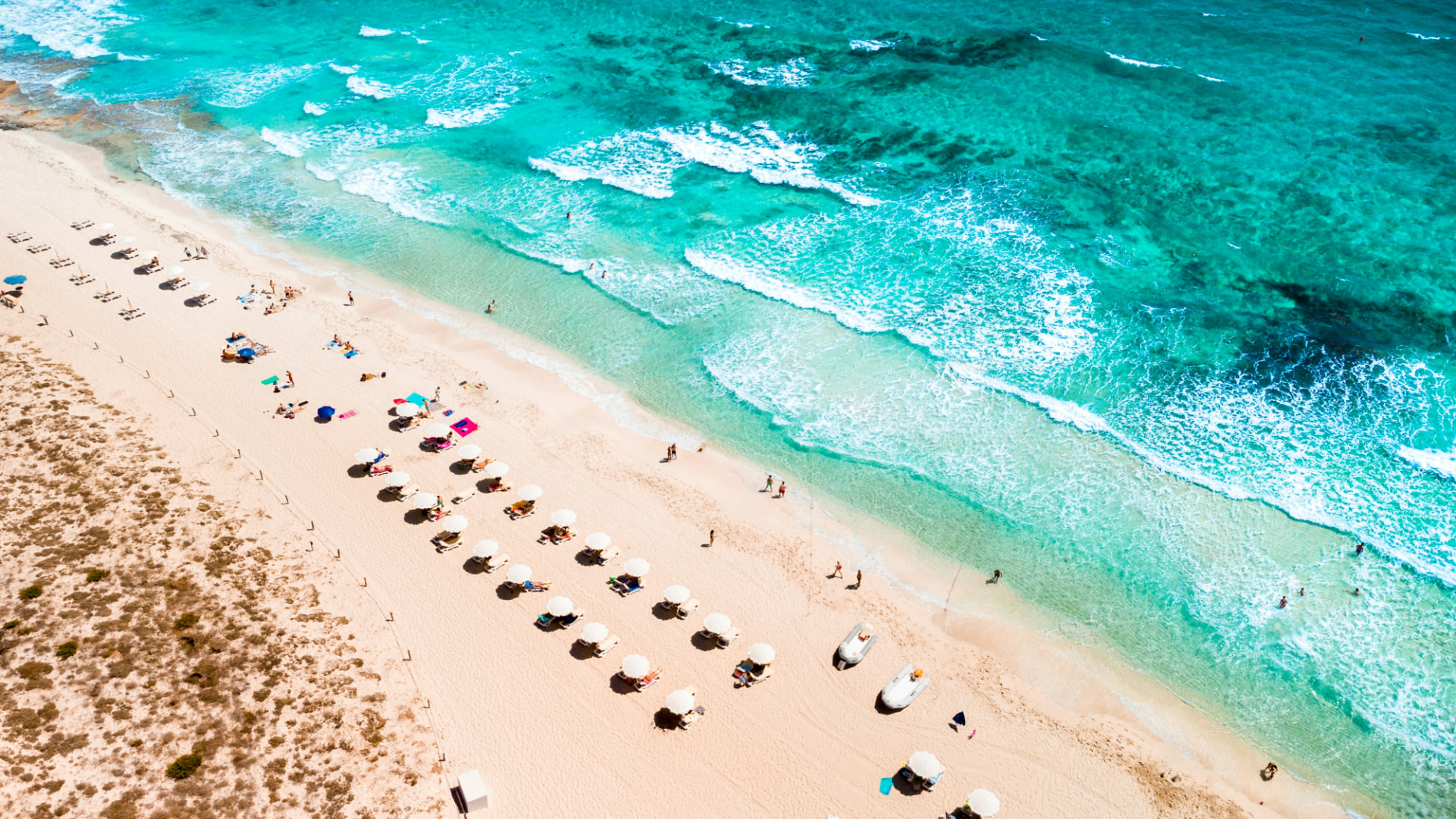Vista aérea de una playa de arena clara y agua turquesa